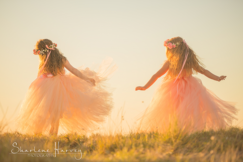 Two girls dancing together on a hill